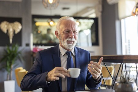 Foto de Hombre de negocios sénior en una reunión en un restaurante, conversando con un socio de negocios y tomando café - Imagen libre de derechos