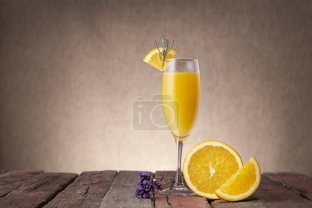 Foto de Cóctel Mimosa en copa de champán con zumo de naranja y vino espumoso decorado con hojas de lavanda y rodajas de naranja - Imagen libre de derechos