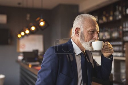 Téléchargez les photos : Homme d'affaires senior prenant une tasse de café dans un immeuble de bureaux moderne cafétéria - en image libre de droit