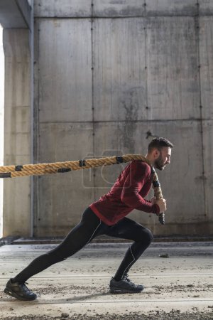 Téléchargez les photos : Athlétique, musclé homme faisant un entraînement fonctionnel de cordes de combat, tirant les cordes, exerçant la force - en image libre de droit