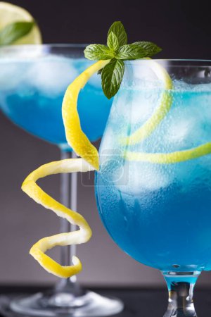 Foto de Detalle de dos cócteles de laguna azul con licor de curazao azul, vodka, zumo de limón y refresco, decorados con rodajas de limón y hojas de menta - Imagen libre de derechos