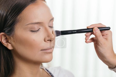 Téléchargez les photos : Maquilleuse maquilleuse maquilleuse, appliquant la poudre visage avec un pinceau de maquillage - en image libre de droit