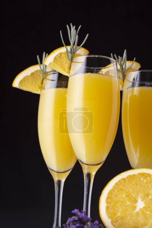 Foto de Detalle de cócteles mimosa en copas de champán con zumo de naranja y vino espumoso decorado con hojas de lavanda y rodajas de naranja. Enfoque selectivo en la rebanada de naranja en el vidrio - Imagen libre de derechos
