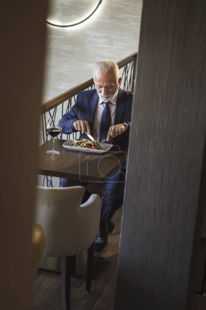 Téléchargez les photos : Homme d'affaires senior prenant une pause, déjeuner dans un restaurant - en image libre de droit