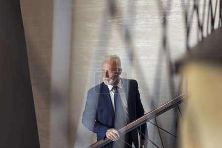 Téléchargez les photos : Homme d'affaires sénior marchant dans les escaliers d'un immeuble de bureaux moderne, se rendant à son lieu de travail - en image libre de droit