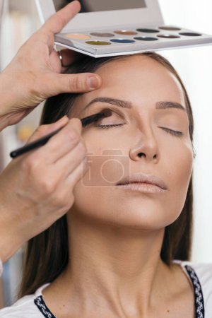 Photo for Make up artist working in a make up studio, shading female client's eyelids - Royalty Free Image