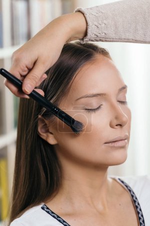 Photo for Make up artist doing the model's make up, applying the face powder with a make up brush - Royalty Free Image