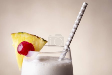 Photo for Detail of pina colada cocktail with dark rum, pineapple juice and coconut cream, decorated with pineapple slices and maraschino cherry - Royalty Free Image