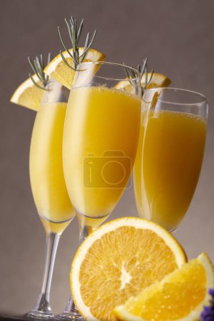 Téléchargez les photos : Cocktails Mimosa dans des verres à champagne au jus d'orange et vin mousseux décoré de feuilles de lavande et de tranches d'orange - en image libre de droit