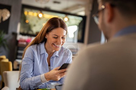 Téléchargez les photos : Couple à un rendez-vous dans un restaurant, en utilisant des téléphones intelligents, en tapant des messages texte et en surfant sur le net - en image libre de droit