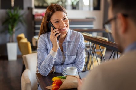 Téléchargez les photos : Jeune femme ayant une conversation téléphonique lors d'un rendez-vous dans un restaurant - en image libre de droit