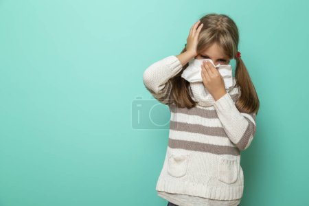 Téléchargez les photos : Portrait d'une petite fille ayant une grippe, de la fièvre et des maux de tête, se mouchant et s'essuyant avec des mouchoirs en papier - en image libre de droit
