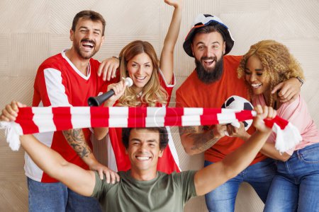 Foto de Grupo de alegres fanáticos del fútbol que usan camisetas deportivas con apoyos animadores preparándose para el juego para comenzar - Imagen libre de derechos