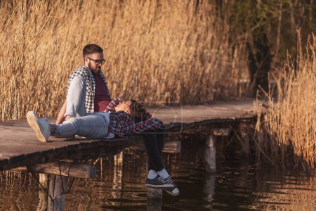 Téléchargez les photos : Couple amoureux profitant d'une belle journée ensoleillée d'automne dans la nature, se détendre aux quais du lac - en image libre de droit