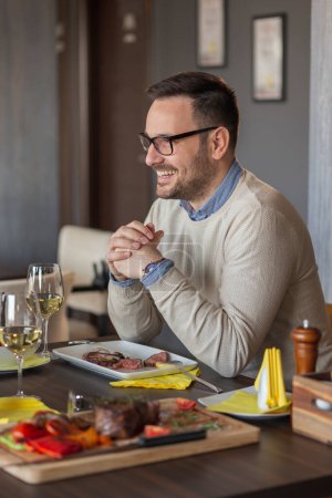 Téléchargez les photos : Homme à un rendez-vous dans un restaurant manger le déjeuner, boire du vin et s'amuser - en image libre de droit
