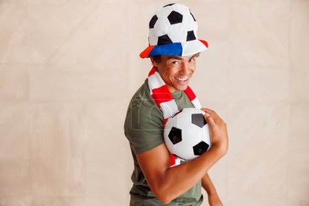 Foto de Retrato de un fanático del fútbol masculino con camiseta deportiva sosteniendo apoyos animadores preparándose para el juego - Imagen libre de derechos