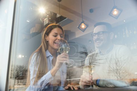 Photo for Portrait of a young couple in love on a date,  sitting at a restaurant table, drinking wine - Royalty Free Image