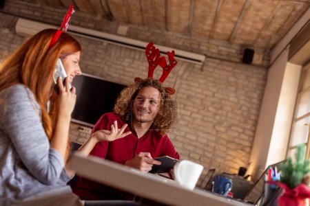 Photo for Business people wearing costume reindeer antlers while organising office Christmas party - Royalty Free Image