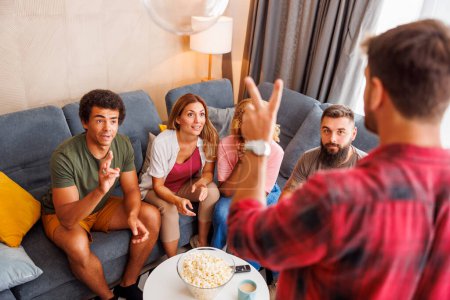 Group of friends having fun playing pantomime while spending leisure time together at home