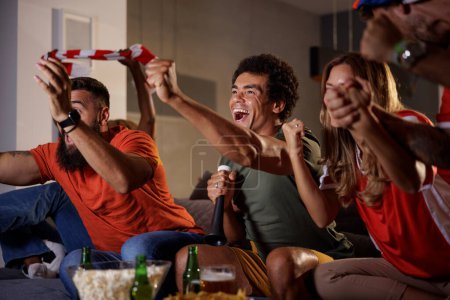 Foto de Grupo de aficionados al fútbol animando mientras ven el partido en la televisión, celebrando que su equipo anote un gol y gane el partido - Imagen libre de derechos