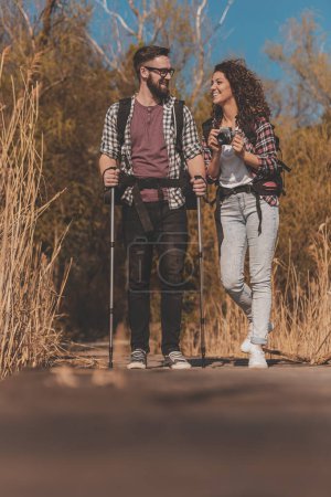 Photo for Couple of backpackers having fun on hiking trip, enjoying sunny summer day outdoors and taking photos - Royalty Free Image