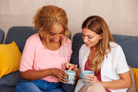 Foto de Dos mujeres se divierten pasando tiempo libre juntas en casa, bebiendo café y leyendo símbolos de la taza después, diciendo fortuna - Imagen libre de derechos