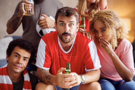 Foto de Grupo de aficionados al fútbol viendo el partido en la televisión enojado y decepcionado después de que su equipo se pierda un gol y perder el juego - Imagen libre de derechos