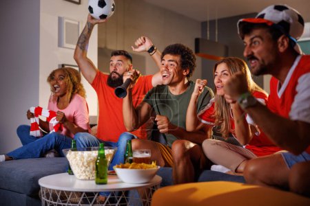 Foto de Grupo de aficionados al fútbol animando mientras ven el partido en la televisión, celebrando que su equipo anote un gol y gane el partido - Imagen libre de derechos