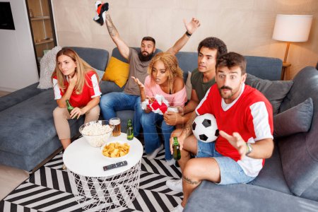 Téléchargez les photos : Groupe d'amis s'amuser à regarder le football à la télévision à la maison déçu après que leur équipe a manqué le but et perdre le match - en image libre de droit