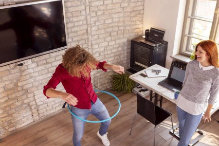 Photo for Business people having fun at the office, playing with hula hoop while on a break - Royalty Free Image
