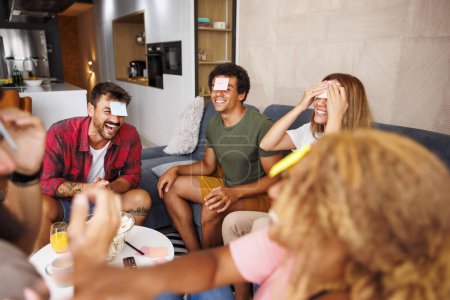 Photo for Group of cheerful young friends having fun at home gathering playing word guessing game charades and pantomime - Royalty Free Image