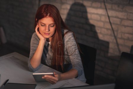 Téléchargez les photos : Femme ayant une conférence téléphonique à l'aide d'un ordinateur tablette tout en travaillant à distance de la maison - en image libre de droit