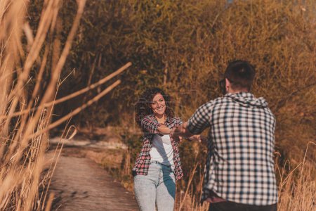Téléchargez les photos : Couple en amoureux profitant d'une belle journée ensoleillée en plein air, s'amusant tout en se tenant la main et tournant sur les quais du lac - en image libre de droit