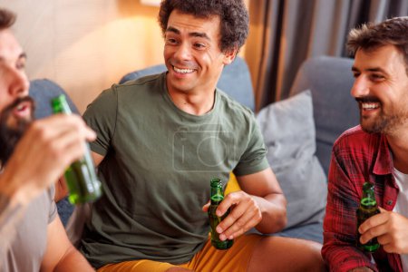 Foto de Grupo de hombres que se divierten pasando tiempo libre juntos en casa, viendo la televisión y bebiendo cerveza - Imagen libre de derechos