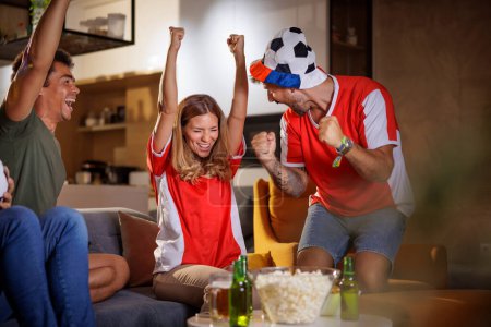 Foto de Grupo de jóvenes amigos viendo el partido de fútbol, celebrando después de que su equipo ha marcado un gol - Imagen libre de derechos