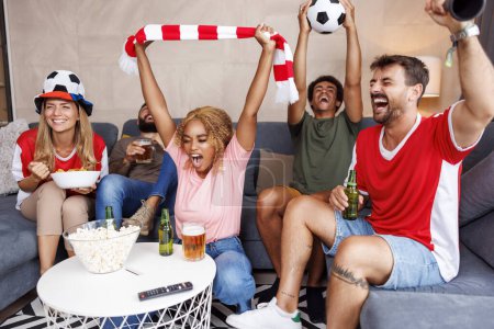 Foto de Grupo de alegres aficionados al fútbol que se divierten animando y celebrando después de que su equipo anote un gol mientras ve el juego del campeonato mundial en la televisión en casa - Imagen libre de derechos