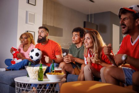 Foto de Grupo de amigos divirtiéndose viendo fútbol en casa decepcionados y enojados después de que su equipo perdiera el gol y perdiera el juego - Imagen libre de derechos