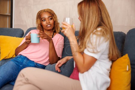 Foto de Dos mujeres disfrutando del tiempo libre en casa, tomando café y teniendo una conversación agradable - Imagen libre de derechos