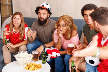 Téléchargez les photos : Groupe d'amis s'amuser à regarder le football à la télévision à la maison déçu après que leur équipe a manqué le but et perdre le match - en image libre de droit