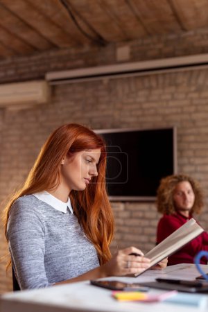Téléchargez les photos : Des gens d'affaires travaillant dans un bureau moderne ; des pigistes travaillant dans un espace de coworking, des femmes lisant les notes d'un planificateur - en image libre de droit