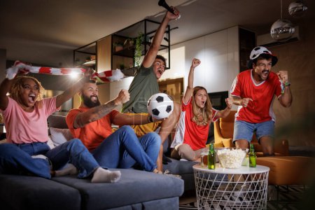 Foto de Grupo de jóvenes aficionados al fútbol viendo el partido en la televisión, celebrando la victoria después de que su equipo haya marcado un gol - Imagen libre de derechos