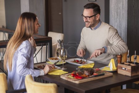 Photo for Couple in love on a date, eating lunch at restaurant, drinking wine and enjoying time spent together - Royalty Free Image