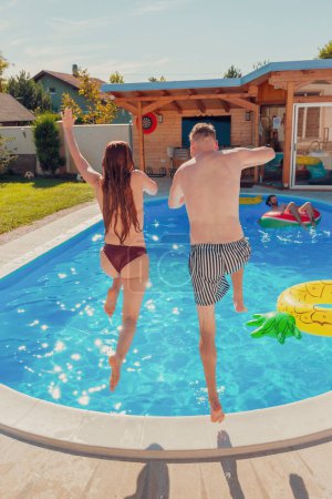 Téléchargez les photos : Beau jeune couple amoureux s'amuser à sauter dans la piscine, se détendre pendant les vacances d'été - en image libre de droit