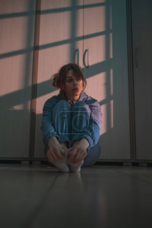 Foto de Mujer con problemas de salud mental sentada en el suelo en la oscuridad con maquillaje manchado después de llorar, molesto y asustado - Imagen libre de derechos