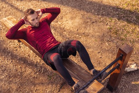 Photo for High angle view of active young man working out outdoors in street workout park, doing crunches - Royalty Free Image