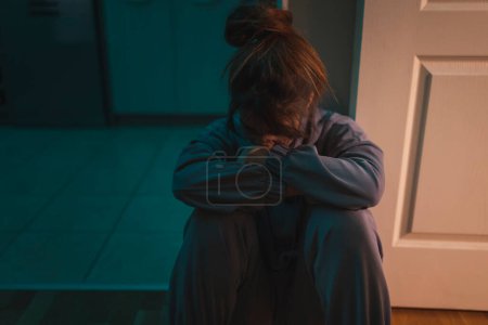 Photo for Woman sitting on the floor in the dark depressed and alone, crying - Royalty Free Image
