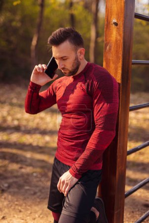 Photo for Active young man having a phone conversation while taking a workout break - Royalty Free Image