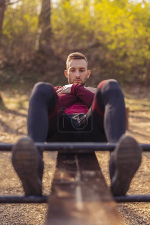 Photo for Active young man working out outdoors in street workout park, doing crunches - Royalty Free Image