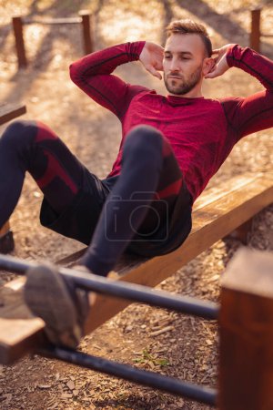 Photo for Active young man working out outdoors in street workout park, holding sitting plank position - Royalty Free Image