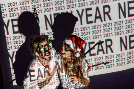 Téléchargez les photos : Beau jeune couple amoureux s'amuser à la fête du Nouvel An, chanter et danser au milieu du neuvième compte à rebours ; couple célébrant le Nouvel An dans une boîte de nuit - en image libre de droit